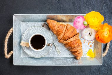 Hafif kahvaltı taze kruvasan ve kahve gri tepsi, tipik çiçekler yakın