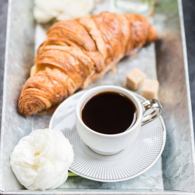 Hafif kahvaltı taze kruvasan ve kahve gri tepsi, tipik çiçekler yakın