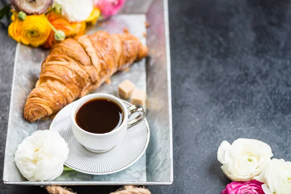 Hafif kahvaltı taze kruvasan ve kahve gri tepsi, tipik çiçekler yakın