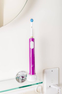 Açık renkli banyo raf üzerinde elektrikli şarj edilebilir diş fırçaları