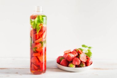 Çilek ve nane ile ışık arka plan üzerinde çilek spor şişe ile su infüzyon detoks