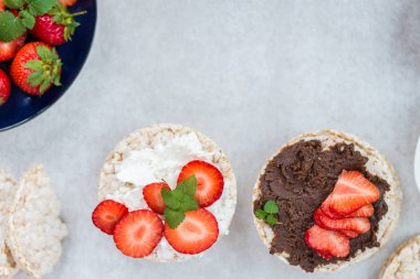 Pirinç kek Ricotta peynir, çikolata fındık yaymak ve ışık arka plan üzerinde çilek gibi malzemelerle gelen sağlıklı Snack