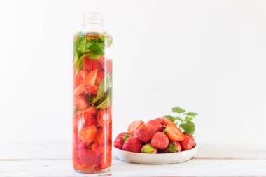 Çilek ve nane ile ışık arka plan üzerinde çilek spor şişe ile su infüzyon detoks