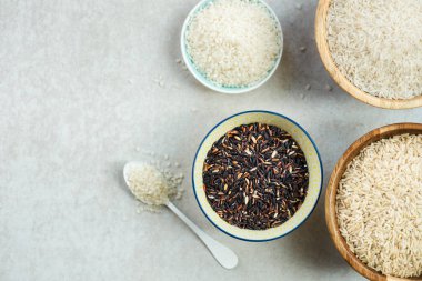 Pirinç ahşap kase basmati, kahverengi ve gri arka plan üzerinde siyah gibi farklı türleri
