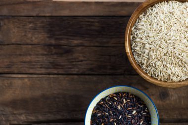 Pirinç ahşap kase basmati, kahverengi ve gri arka plan üzerinde siyah gibi farklı türleri