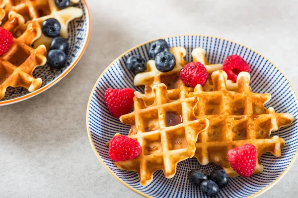 Traditional homemade belgian waffles with fresh berries and syrup on light background.  Cosy family breakfast concept.  Flat lay, top view.