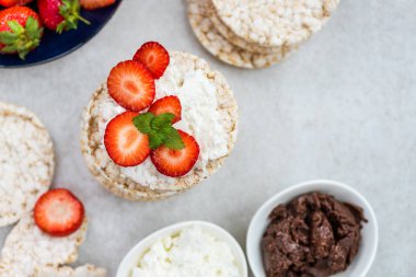Pirinç kek Ricotta peynir, çikolata fındık yaymak ve ışık arka plan üzerinde çilek gibi malzemelerle gelen sağlıklı Snack