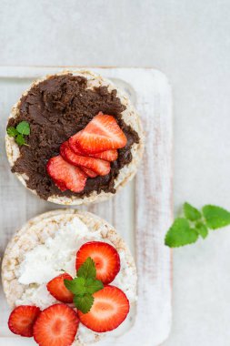 Pirinç kek Ricotta peynir, çikolata fındık yaymak ve ışık arka plan üzerinde çilek gibi malzemelerle gelen sağlıklı Snack