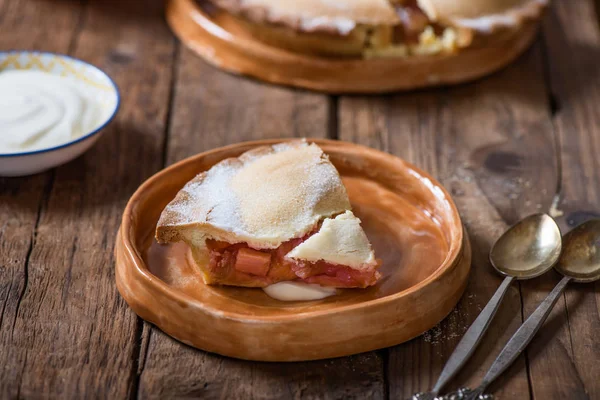 Piece of fresh rhubarb and strawberry pie with cream nearby — Stock Photo, Image