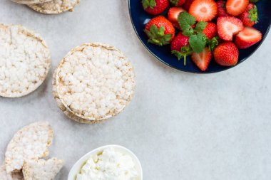 Pirinç kek Ricotta peyniri ve ışık arka plan üzerinde çilek gibi malzemelerle gelen sağlıklı Snack