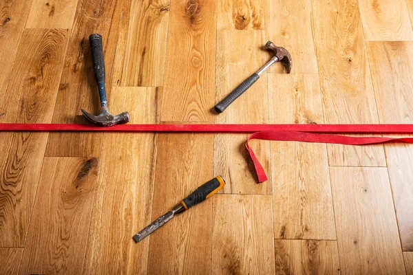 The process of house renovation with changing of the floor from carpets to solid oak wood. Different tools and materials on the new floor