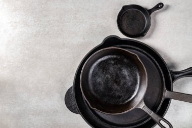 Birkaç dökme demir tava veya Skillets gri arka plan üzerinde sağlıklı yemek pişirmek için