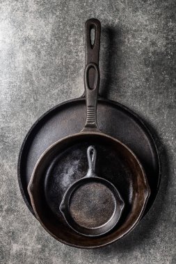 Birkaç dökme demir tava veya Skillets gri arka plan üzerinde sağlıklı yemek pişirmek için
