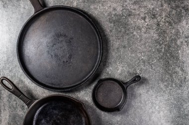 Birkaç dökme demir tava veya Skillets gri arka plan üzerinde sağlıklı yemek pişirmek için