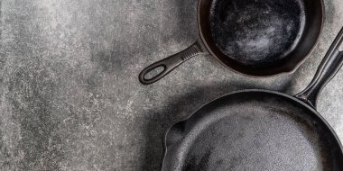 Birkaç dökme demir tava veya Skillets gri arka plan üzerinde sağlıklı yemek pişirmek için
