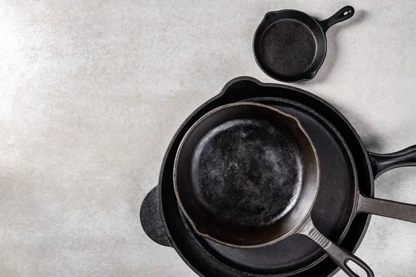 Birkaç dökme demir tava veya Skillets gri arka plan üzerinde sağlıklı yemek pişirmek için