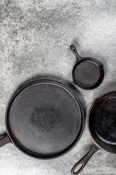 Several Cast Iron Pans or Skillets for Healthy Cooking on Grey Background