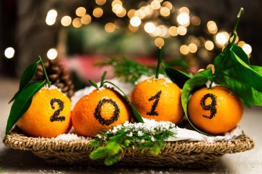 Yeni yıl 2019 geliyor kavramdır. Sepet çam sopa ve arka planda Xmas Lights ile döşeme portakal üzerinde siyah mürekkeple yazılmış sayılar