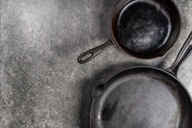 Birkaç dökme demir tava veya Skillets gri arka plan üzerinde sağlıklı yemek pişirmek için