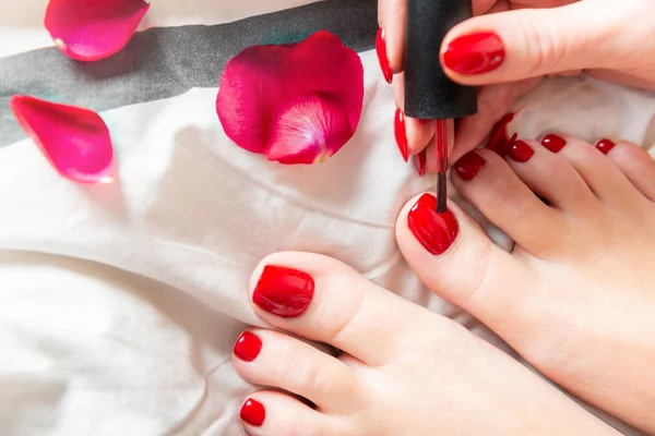 Young lady is applying red polish on toes — Stock Photo, Image