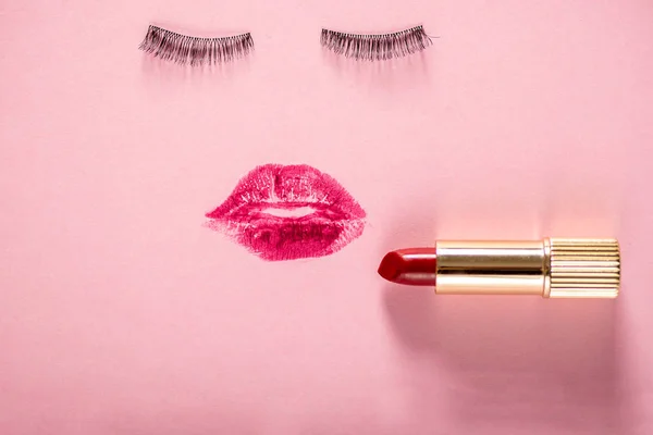 Creative woman face made of eyelashes, wig eyebrows and red lipstick stains as lips. Minimal beauty concept. Hair loss products. Pink backgroung, fashion flat lay