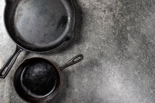 Birkaç dökme demir tava veya Skillets gri arka plan üzerinde sağlıklı yemek pişirmek için