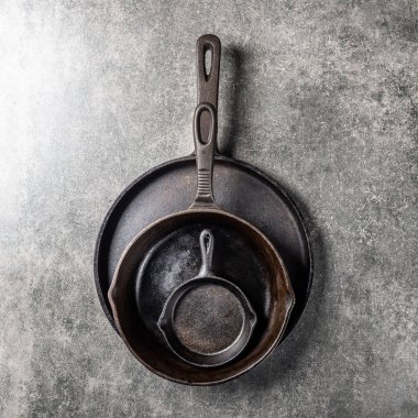 Birkaç dökme demir tava veya Skillets gri arka plan üzerinde sağlıklı yemek pişirmek için