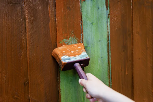 Painting old wooden fence with a brown paint — Stock Photo, Image