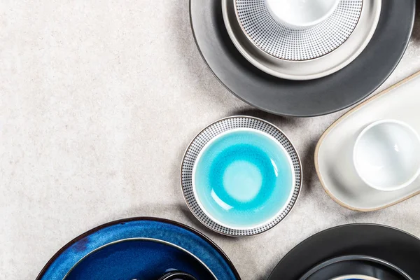 Пустые голубые и черные тарелки с кружками на сером фоне — стоковое фото