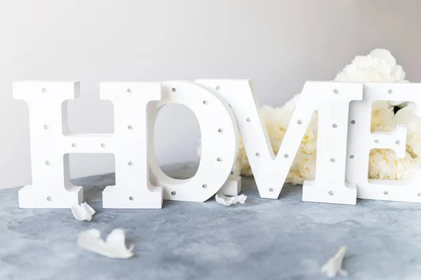 Bunch of amazing peonies and wooden letters HOME — Stock Photo, Image