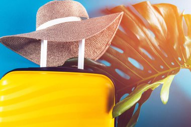 Parlak ve şık kabin büyüklüğünde hasır şapkalı bavul.