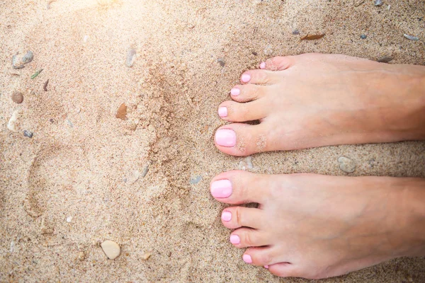 Fiatal hölgy megmutatja neki fény rózsaszín pedikűr körmök homokos strandon háttérben — Stock Fotó