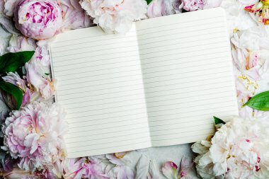 Pembe şakayık çiçeklerinden yapılmış çerçeve ve açık bir defter