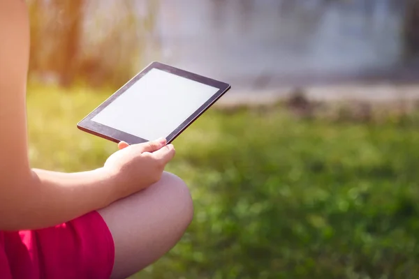 Chica joven está leyendo ebook en el banco cerca del mar — Foto de Stock