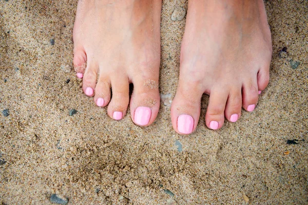 Jovem senhora está mostrando suas unhas pedicure rosa claro na praia de areia backgroung — Fotografia de Stock