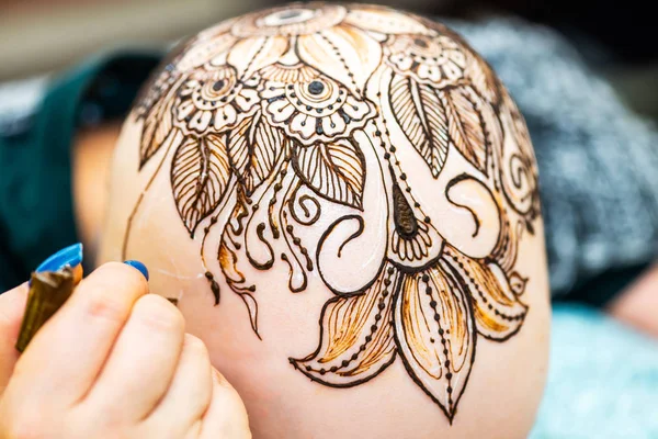 Drawing process of henna mehndi ornament on womans head