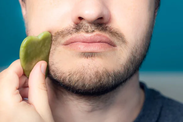 Bearded man is using jade face roller — Stock Photo, Image