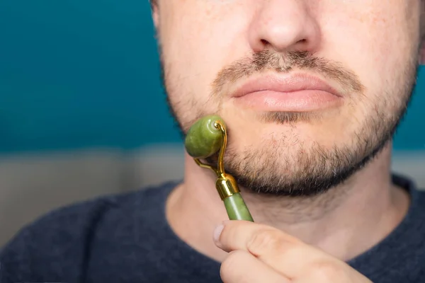 Bearded man is using jade face roller — Stock Photo, Image