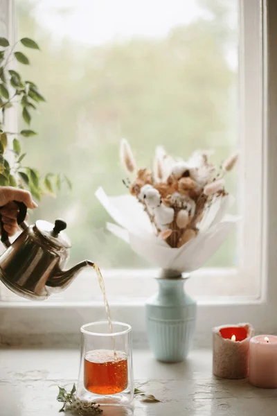 Çay demliyorum. Eski vitrinde siyah çay ve duble cam bardak. El yapımı çay. Vazodaki çiçekler ve arkadaki mumlar..