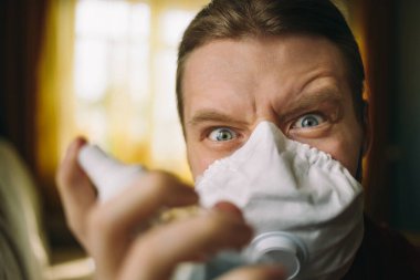 Elinde antiseptik olan, koronavirüs maskeli deli bir adamın portresi.