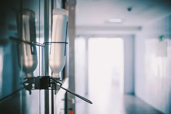 Hastane koridorunda el dezenfektanı var.