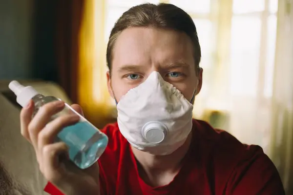 Coronavirus maskeli ve elinde antiseptikle genç bir adamın portresi.
