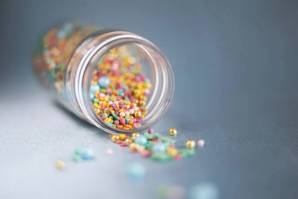 Cam kavanozdan dökülen renkli şekerleme, mavi arka planda pasta ve fırın dekorasyonu. Makro