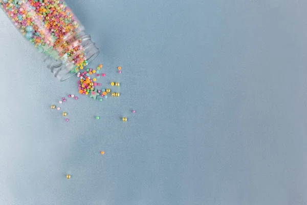 Cam kavanozdan serpilmiş üst manzara. Renkli şekerleme serpiştirme, pasta süsleme ve fırın için mavi zemin