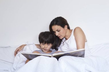 Anne ve oğul yatakta yatan bir kitap okuma