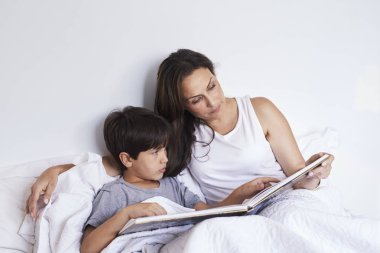 Anne çocuğun yatakta okuma