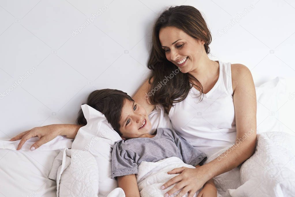 Laughing mom and kid in bed, smiling