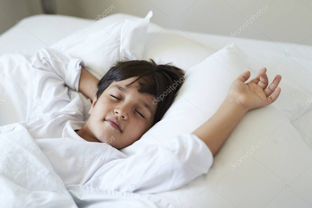 Sleeping boy lying on back in bed