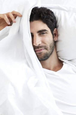 Adam beyaz çarşafın altında yalan yatakta