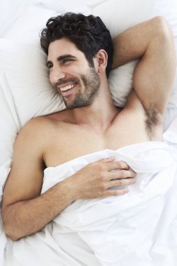 Yatakta rahatlatıcı, uzağa bakarak adam gülümseyen 
